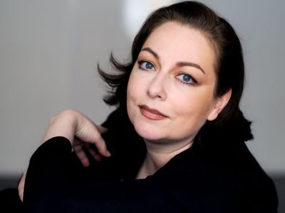 Dorothea Röschmann wearing a long sleeve black top looking at the camera smiling